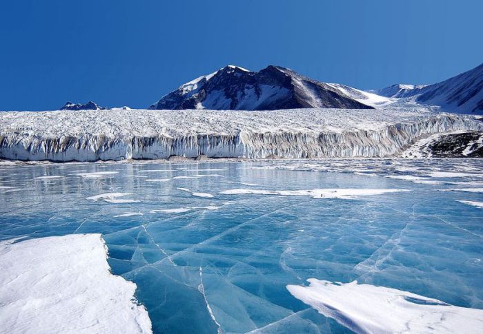 Antarctica: The blue ice covering Lake Fryxell, in the Transantarctic Mountains, comes from glacial meltwater from the Canada Glacier and other smaller glaciers. The freshwater stays on top of the lake and freezes, sealing in briny water below.